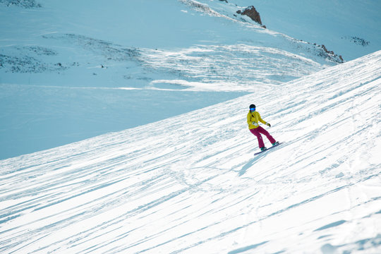 Photo of sports girl wearing helmet and mask, snowboarding from mountain slope