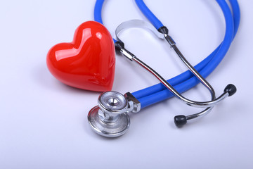 Stethoscope and red heart on white table with space for text.