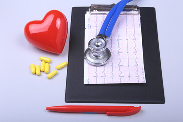 Stethoscope, red heart, RX prescription and assorted pills on white table with space for text.