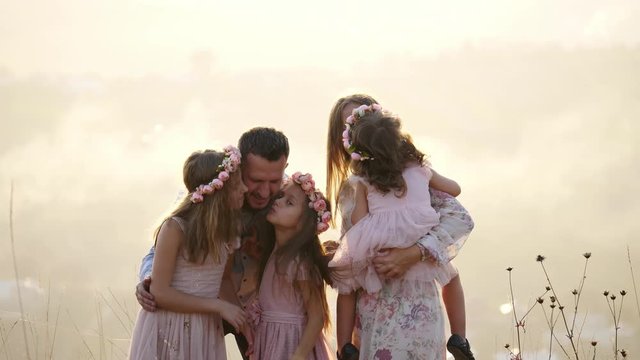 Portrait of happy family with their doughters sits in the meadow.