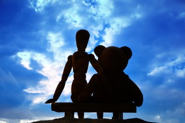 Beste Freunde auf Bank in Rückenansicht vor blauem Himmel mit Wolken