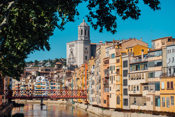 Colorful yellow and orange houses and bridge Pont de Sant Agusti reflected in water river Onyar, in Girona, Catalonia, Spain.