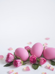 Decorative Easter eggs and pink roses on light background. Holiday card.