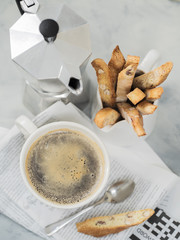 Biscotti (cantuccini) - traditional Italian almond dessert with cup of coffee and Moka coffee pot on newspaper.
