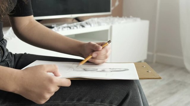 A young woman learns to draw. Woman artist paints a model at home. Close-up