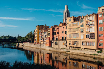 Obraz premium Colorful yellow and orange houses and bridge Pont de Sant Agusti reflected in water river Onyar, in Girona, Catalonia, Spain.