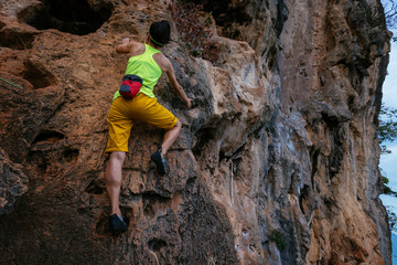 female rock climber climbing on seaside cliff
