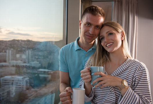 young couple enjoying evening coffee by the window