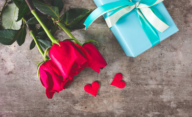 Top view of blooming red roses, hearts decoration and blue wrapped gift with ribbon. Love, present or valentines concept