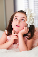 Naklejka premium 6 or 7 Years Old Little girl with Dark Hair and Brown Eyes, with White Flower Headband,Funny Expression, dreaming, happy posing isolated on blurry background 