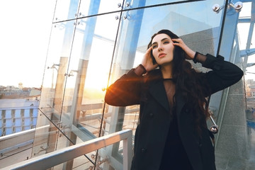 young successful beautiful girl stands on the roof of a building on a high rise background