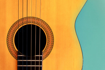Acoustic classic guitar on blue background. Simple musical instrument with copy space.