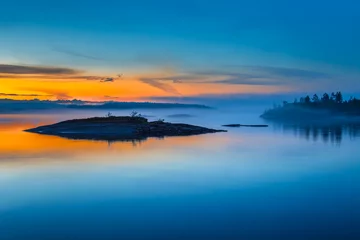 Nebel über dem See. Sonnenaufgang im Nebel. Wilde Natur Finnlands. Inseln aus Stein. Spiegelbild im Wasser. Sommer in Finnland. © Grispb