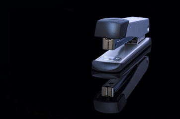 Stapler and reflection on black background