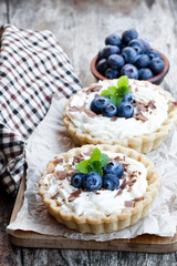 Delicious  tarts with cream and fresh blueberry on wooden table
