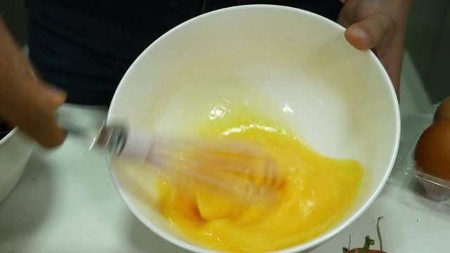 4k of woman cooking and whisking eggs in a bowl in kitchen room
