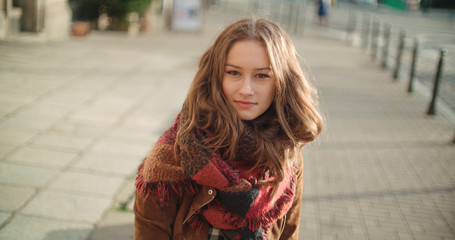 Fototapeta premium Portrait of beautiful young woman standing in a city street and smiling.