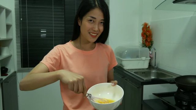 4k of woman cooking and whisking eggs in a bowl in kitchen room