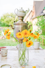 Bouquet of coreopsis and samovar with a teapot on summer terrace in the fresh air
