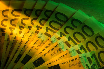 Ten Euro banknotes tidy with a yellow light coming from the left and a green light from the right