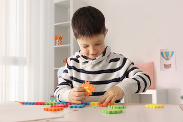 Cute little boy playing with figures while doing homework indoors