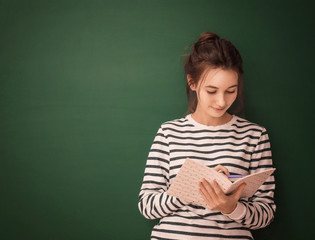 Cute teenager girl with notebook on green background