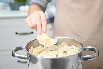 Woman cooking dumplings in boiling water, closeup