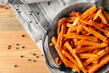 Pan with sweet potato fries on wooden table, top view