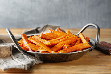 Pan with sweet potato fries on wooden table