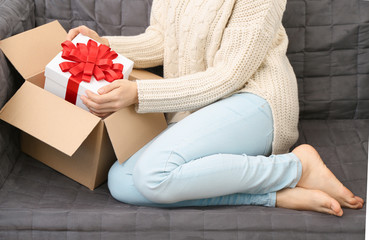 Woman taking gift box out of parcel at home