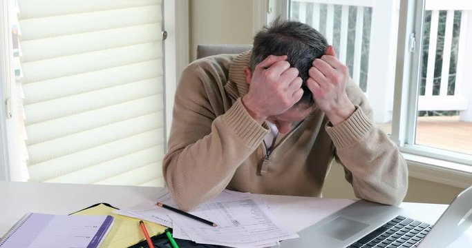 Mature man very angry while doing his income taxes 