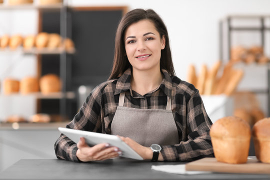 Young woman using tablet computer in bakery. Small business owner