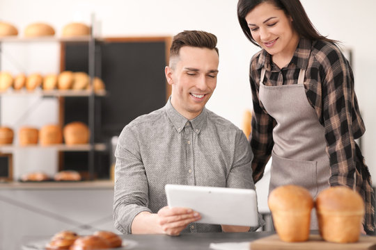 Young people using tablet computer in bakery. Small business owners