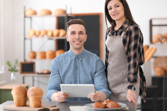 Young people using tablet computer in bakery. Small business owners