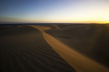 Fototapeta na wymiar warm sandy dunes at canary islands while sunset, hot orange desert, epic side view 