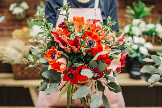 Anonymous worker of floral shop holding amazing creative bouquet in hands. 