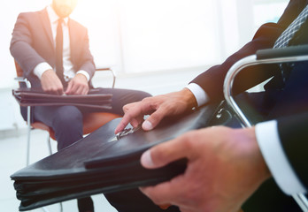 Man in a classic suit holds a brown briefcase close-up