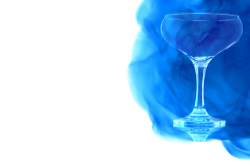 An empty glass of champagne enveloped in blue smoke.