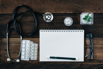 stethoscope, medicine and notebook on wooden table background. healthcare and medical concept