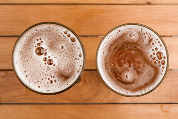 Two mug of beer with bubble on glass on top view wooden background