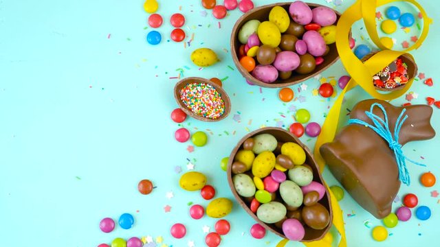 Happy Easter decadent chocolate background overhead with Easter eggs and candy on a rustic wood background with copy space.