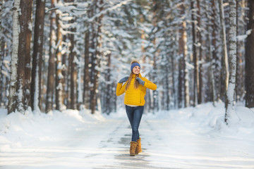 Young smiling woman in a bright clothes stands on a road in a winter forest