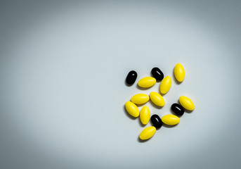 Macro shot of yellow oval tablet pills and black tablets pills on white background with copy space...