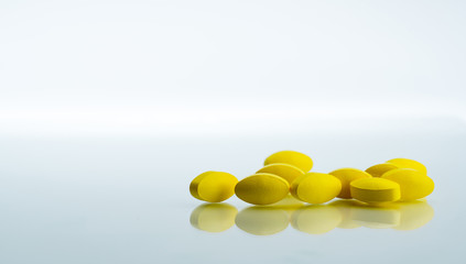 Pile of yellow oval tablet pills on white background with copy space for text. Mild to moderate pain management. Pain killer medicine. Medicine for relieve high fever.