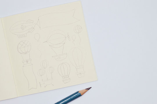 notebook with pencil sketches of balloons on white background