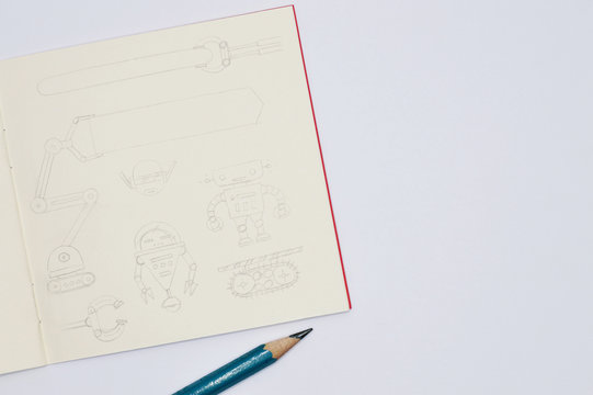 notebook with pencil sketches of robots on white background