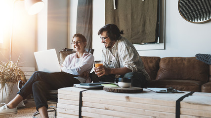 Group of two people with laptops in small loft office. Man and woman working together. Discussing positive feedback
