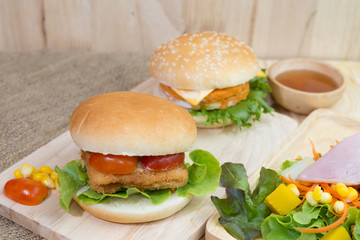 Selective focus of two hamburgers and salad on wood table.
