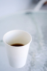 Paper (disposable) white cup with coffee close-up. Blurred background. Top and side view with copy space