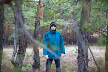 A rural guy posing in a pine forest in the autumn time.